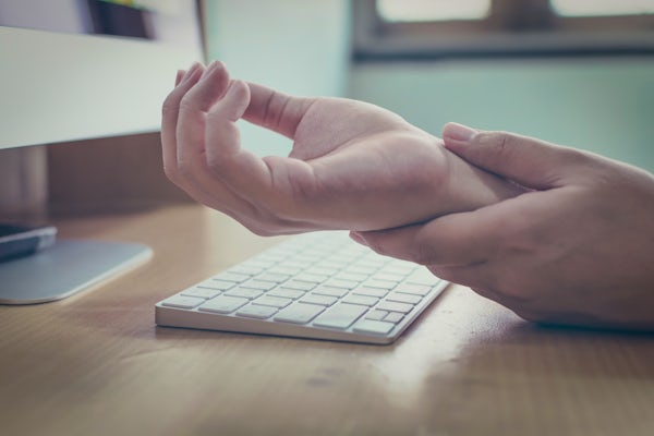 person rubs wrist while using computer
