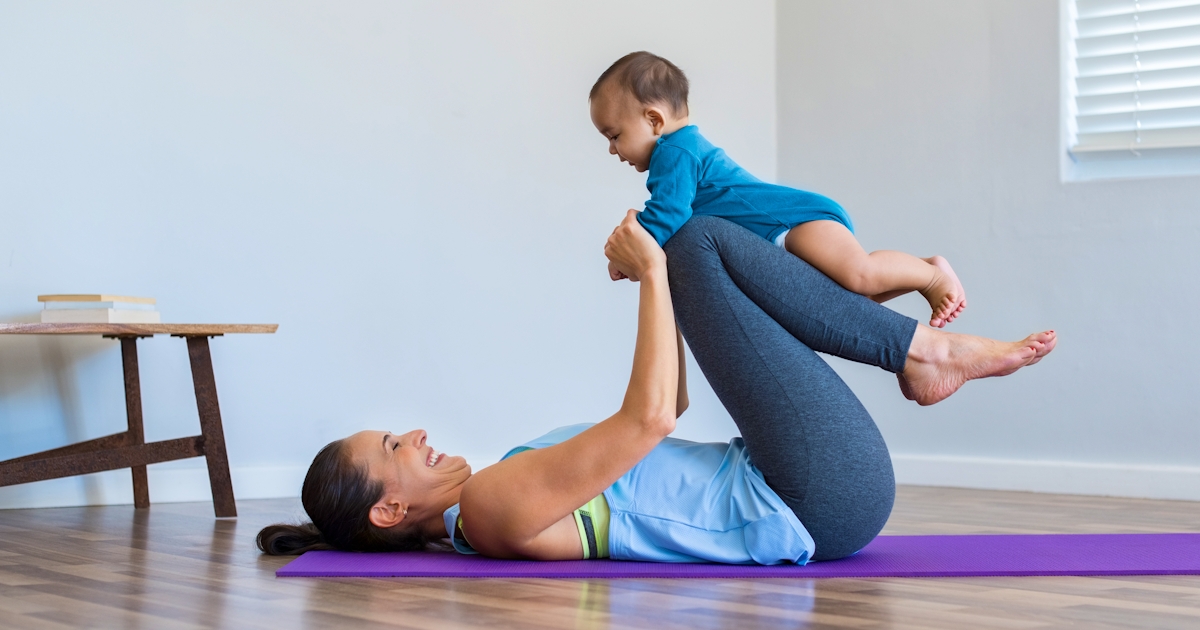 mother with baby on yoga mat in studio having fun