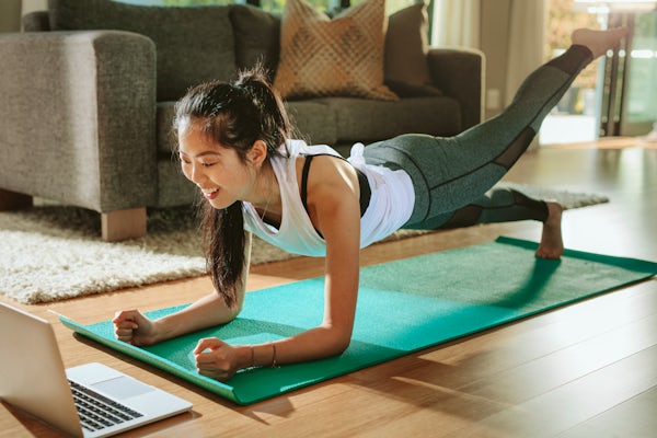 Woman watching sports training online on laptop.